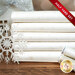 A stack of the fabrics included in the Half Yard Set White/Pearl by Stof Fabrics, with a glass house, a snowflake, and thread.