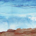 Abstract fabric featuring soft blue skies with wispy clouds above warm earth-toned rock formations.