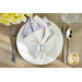 A top down shot of a place setting with the reversible white floral fabric of the napkin faced out.