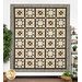 The completed Garden Stars quilt colored in warm tan and charcoal fabrics, hung on a white-paneled wall and bordered by color-coordinated decor.