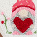 Close up of embroidery design featuring a gnome holding a heart surrounded by florals