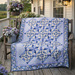 A blue and cream quilt with intricate star patterns draped over a wooden bench on a porch.