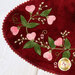 A super close up on the pink wool hearts and green embroidered leaves and buds, showing stitching details.