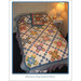 A colorful quilt with floral patterns drapes over a bed, complemented by a matching pillow and lamp.