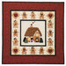 A quilt featuring a gingerbread house surrounded by gingerbread figures and hearts in a festive border.