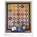 A colorful patterned quilt hangs on a wall, surrounded by a vintage kettle and basket on a table.