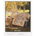 A colorful quilt draped over a rustic bench in a serene outdoor setting among birch trees.