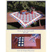 Image features a red, white, and blue quilt on a picnic table with apples and a vase, and a placemat below.