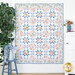 A floral-patterned quilt featuring blue and pink colors with a geometric design hangs on a wall