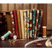 A stack of the fabrics included in the Stitchin' FQ set, with spools and scissors and buttons and a tape measure.