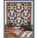 A decorative quilt featuring floral and leafy patterns, displayed with apples and a matching table runner.