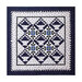 A quilt featuring a diamond pattern with blue flowers, framed by a zigzag border on a dark background.