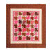 A quilt featuring a pattern of colorful leaves in shades of pink, brown, and red, framed by borders.