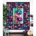 The completed Stained Glass Panel quilt colored in pink, teal, and purple floral fabrics, hung on a white paneled wall and bordered by coordinating floral decor.