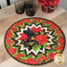 A round floral table mat featuring vibrant red flowers and green leaves, set on a wooden table.