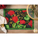 A floral placemat with red geraniums, green leaves, and decorative gold accents on a black background.