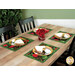 A dining table set with four plates, gold utensils, napkins, and a vase of red flowers in the center.