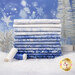 A stack of fabrics in the Ice collection featuring cool blue and white tones, in front of a blue, snowy background with blue and white thread