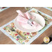 A beautifully set dining table with a floral placemat, white plate, and pink napkin in a silver ring.