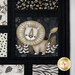 Close-up of fabric featuring a cute, stylized lion with a fluffy mane against a dark background surrounded by other animal prints