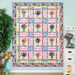 The completed Baltimore Quilt, colored in vibrant watercolor style fabrics from the Garden Fresh collection. The quilt is hung on a white paneled wall and staged with coordinating bouquets and decor.