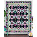 The completed Belle Kaleidoscope quilt colored in purple and aqua floral fabrics from Shizuka, hung on a white paneled wall and bordered by aqua and purple coordinating decor.