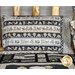 A pillow with patterned fabric featuring animal prints and a coordinated quilt in a rustic setting.