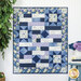 The completed Comfort of Psalms quilt featuring the Morning Blooms collection in shades of blue with floral patterns and inspirational text hung against a wall next to coordinating decor