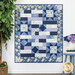 The completed Comfort of Psalms quilt featuring the Morning Blooms collection in shades of blue with floral patterns and inspirational text hung against a wall next to coordinating decor