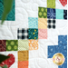 Colorful quilt patchwork featuring various patterns on a white background with quilting details.