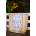 A shot of the quilt draped over a white fence in front of trees.