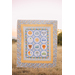 A shot of someone holding up the panel quilt in front of a field.