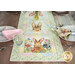 A colorful table runner with bunny illustrations and floral designs on a wooden dining table.