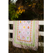 A shot of the quilt draped over a white fence in front of trees.