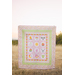 A shot of someone holding up the panel quilt in front of a field.