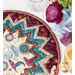 Colorful quilted table topper featuring celestial patterns and a starburst design next to a candle and floral arrangements.