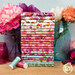 A stack of colorful fabrics in the Zinnias Fat Quarter Set featuring floral designs, with jars and flowers and buttons and thread.