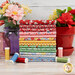 A stack of colorful fat quarters staged with vibrant flowers and spools of thread.