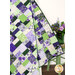 A close up on the draped quilt, demonstrating flow and form as well as fabric colors. Coordinating flowers sit on the right side of the frame.