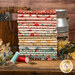 A stack of the fabrics in the Farmhouse Fancy fat quarter set featuring a variety of floral prints, with a bucket and a jug and flowers and thread.