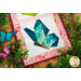 A close up on the lower butterfly surrounding by decorative leaves and fake butterfly decor, demonstrating fabric, piecing, border, and binding details.