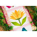 A close up on the center flower surrounding by decorative leaves, demonstrating fabric, piecing, border, and binding details.