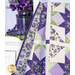 A close up of the quilt draped over a white ladder in front of a white dresser holding coordinating purple florals, demonstrating form and movement.