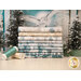 A stack of the fabrics included in the Winter Whispers Collection, with snowy trees and thread.