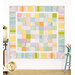 A colorful patchwork quilt displayed on a wall, featuring a variety of pastel patterns and textures.