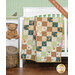 A patchwork quilt draped over a crib, featuring earthy tones and whimsical animal patterns next to coordinating decor. 