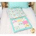 A shot of the quillow partly unfolded featuring playful cat designs staged on a bed with matching fabrics.