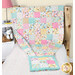 A shot of the quillow almost all the way unfolded featuring playful cat designs staged on a bed with matching fabrics next to coordinating decor.
