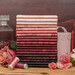 A stack of Operetta fabrics in shades of pink, surrounded by flowers and spools of thread.