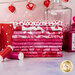 A stack of fabrics included in the Forever Love collection with red, pink and white fabrics with a Valentine's Day theme, with bottles and a mug and lights and thread.